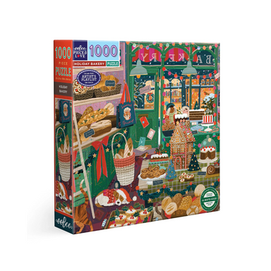 An image of a 1000 piece puzzle box set against a white background. The image on the puzzle is an artists depiction of the inside of a bakery shop during the holidays. There is a dog sleeping on the floor with a Santa hat on, Holiday decorations all over the walls and windows, and piles of breads, cakes, cookies, and gingerbread houses. Outside of the shops windows its snowing and you can see sids pressing their faces against the glass to see the bakery sweets. The image invokes feelings of coziness!