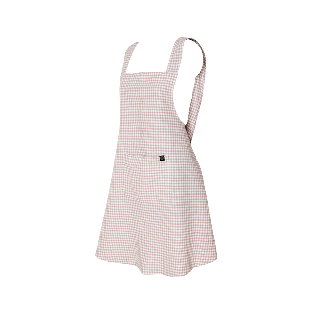 an Image of a light pink gingham linen-cotton blend apron on a white background. 